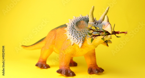 toy in the shape of a dinosaur on a yellow background close-up selective focus.