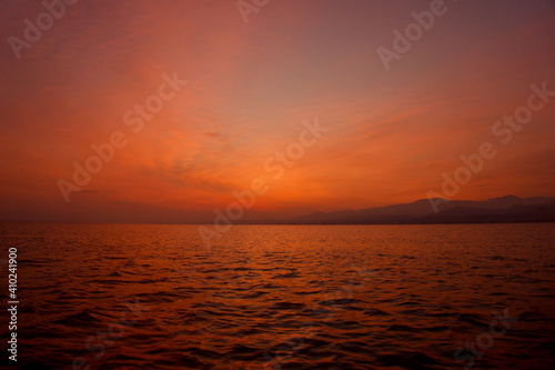 Sunrise from Catamaran Yacht over the sea with mountains in the background in Sicily. Low light photo of sunrise over the Mediterranean sea. 