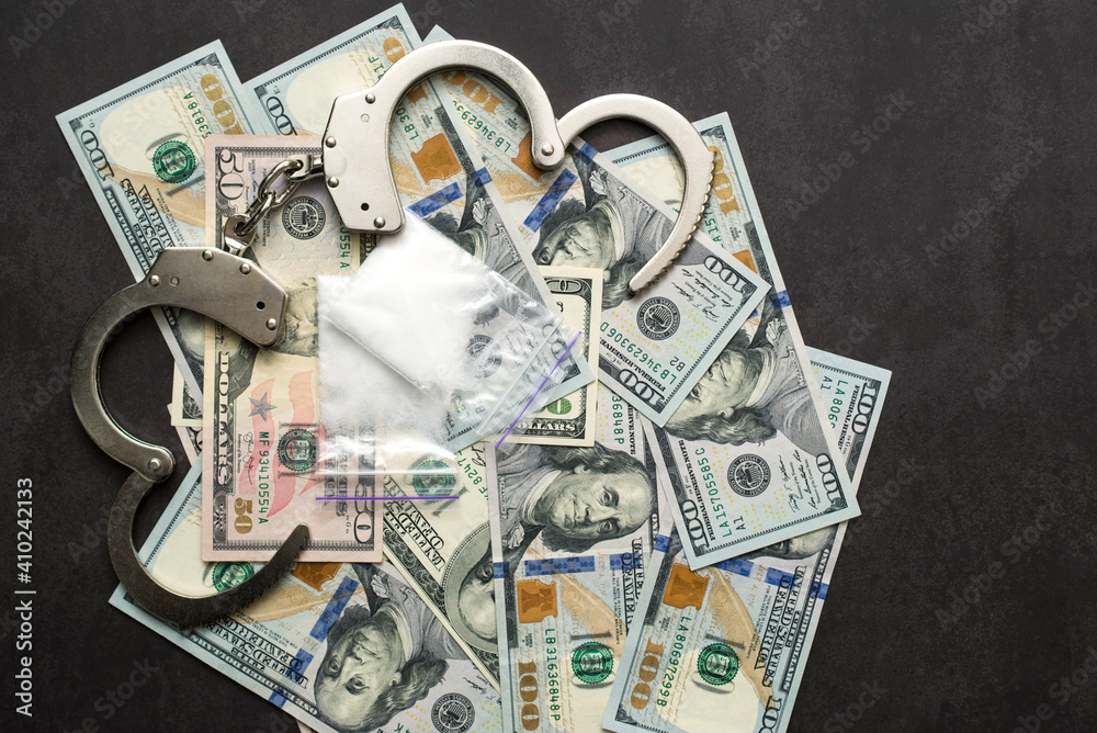Money, drugs and handcuffs. Handcuffs, money and cocaine drugs on dark background close up Money, drugs and handcuffs. Handcuffs, money and cocaine drugs on dark background close up