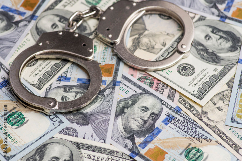 Handcuffs on money background. Dollar bills, money cash corruption, dirty money financial crime and metal police handcuffs Handcuffs on money background. Dollar bills, money cash corruption, dirty money financial crime and metal police handcuffs