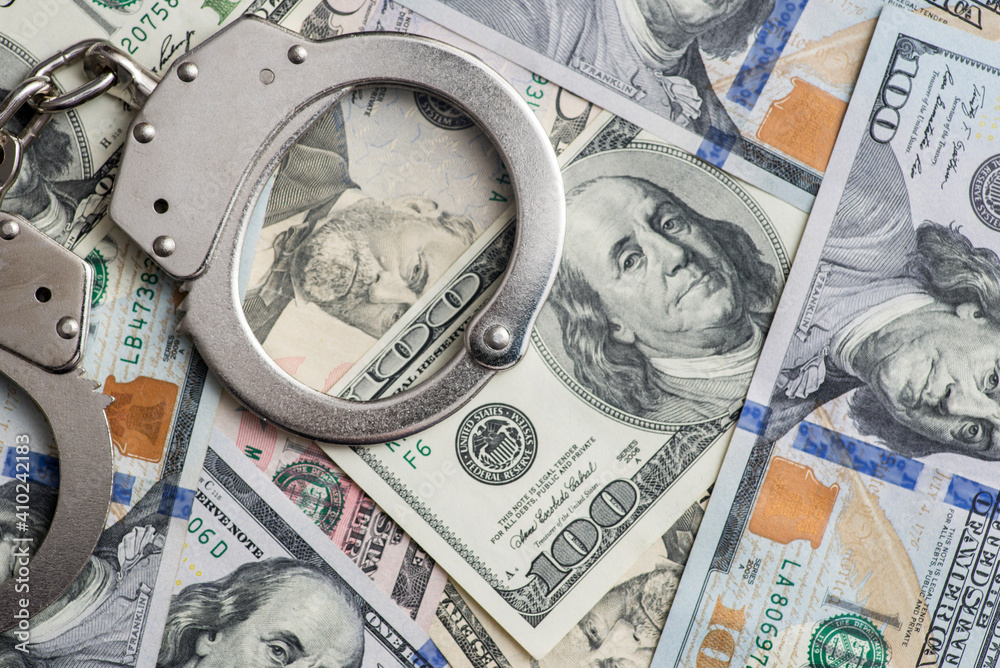 Handcuffs on money background. Dollar bills, money cash corruption, dirty money financial crime and metal police handcuffs