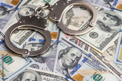 Handcuffs on money background. Dollar bills, money cash corruption, dirty money financial crime and metal police handcuffs