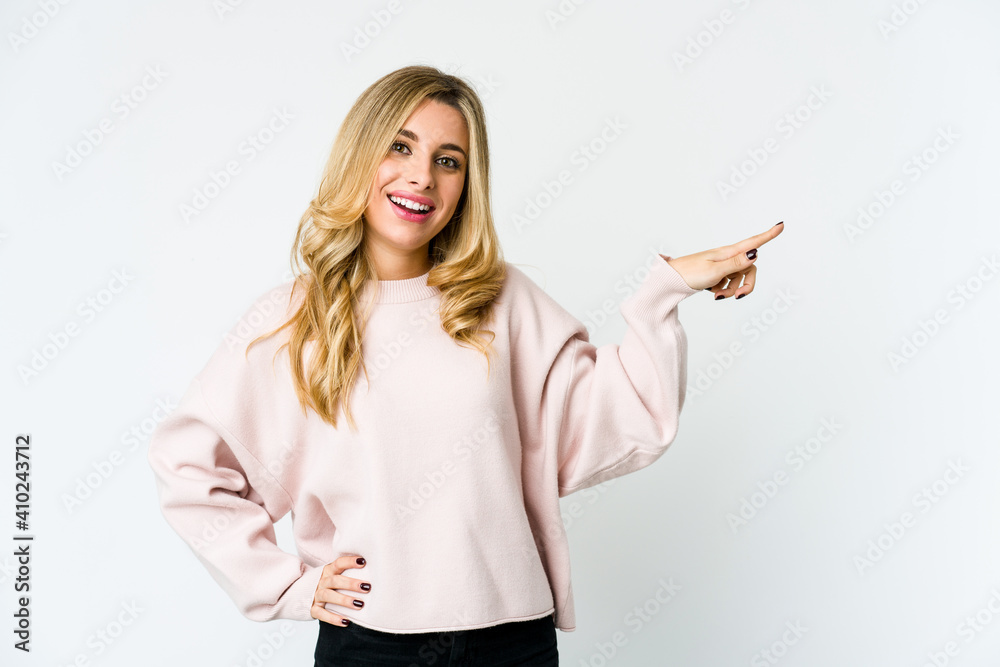 Young caucasian blonde woman smiling cheerfully pointing with forefinger away. Young caucasian blonde woman smiling cheerfully pointing with forefinger away.