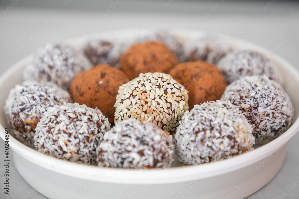 Handmade coconut snow balls made from dates, almond and coconut truffles on grey surface, healthy eating cocept