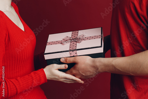 Valentine Day Gift. Happy Young Couple with Valentine's Day Present isolated on red background.