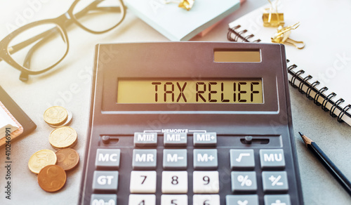 Word TAX RELIEF. Written on a calculator on an office desk.