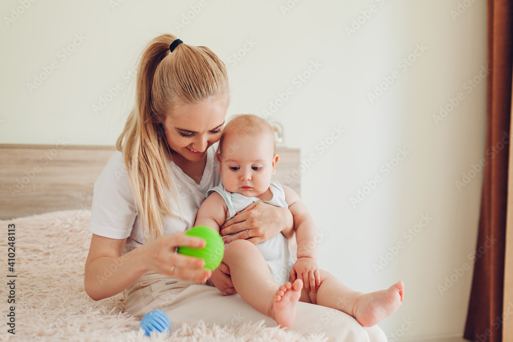 Mother playing with her newborn baby son at home. Family having fun. Infant biting ball. Mother's day Mother playing with her newborn baby son at home. Family having fun. Infant biting ball. Mother's day