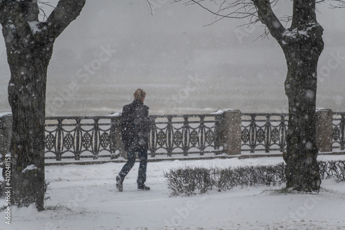 a passer-by walks along the embankment in a heavy snowfall. snowfall in the city.
