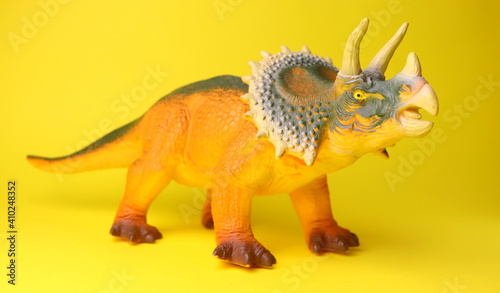 toy dinosaur close-up on a yellow background selective focus, childrens toys. © Olga
