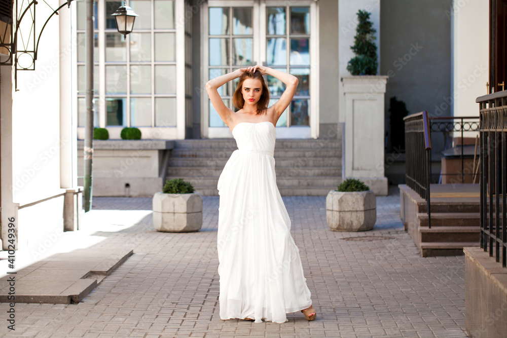 Obraz premium Full length portrait of beautiful model woman with long legs wearing white dress