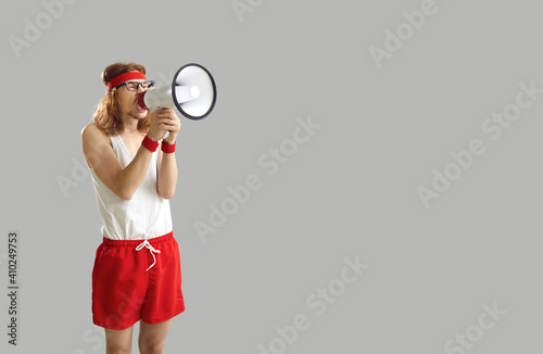 Fotografie Funny noisy crazy nerdy man in sports shorts yelling in megaphone, announcing im