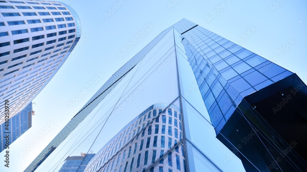 Fototapeta premium Glass facade of the buildings with a blue sky. Skyscrapers in the business city center.. Background of modern glass buildings. 