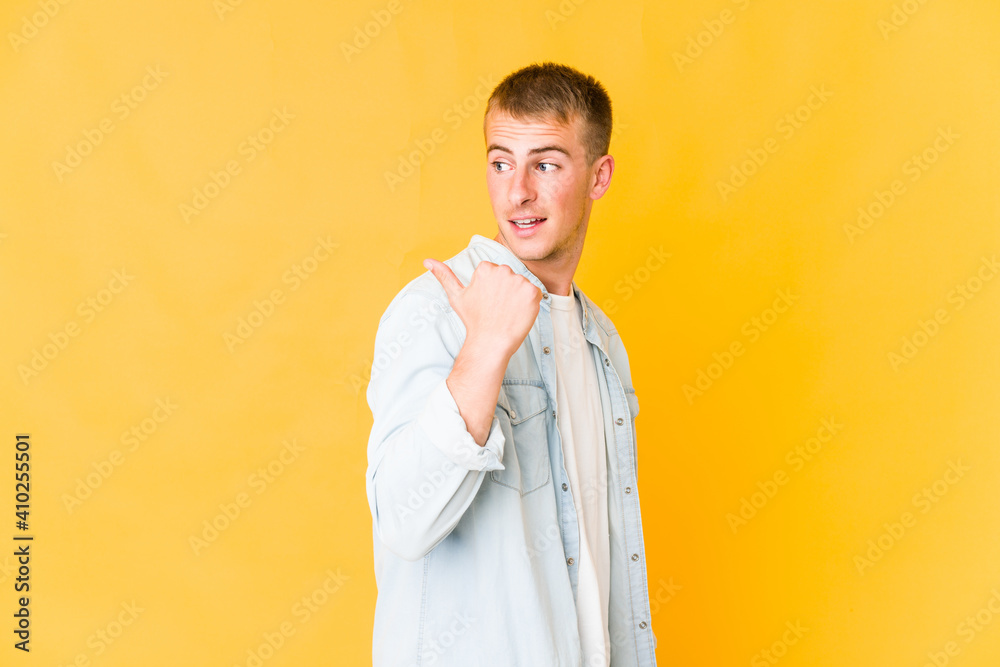 Young caucasian handsome man points with thumb finger away, laughing and carefree. Young caucasian handsome man points with thumb finger away, laughing and carefree.