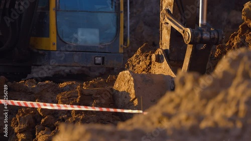 In winter, at a construction site, excavator remove a layer of earth to build the foundation of the future structure and load it into the bodies of dump truck