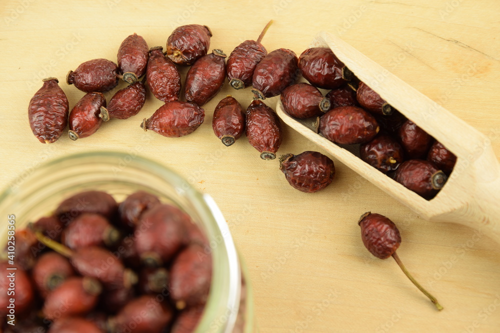 Rose hips, dried wild rose fruits on wooden spoon and jar, natural wooden background, super food, healthy fruits, vitamin C and antioxidants resource Rose hips, dried wild rose fruits on wooden spoon and jar, natural wooden background, super food, healthy fruits, vitamin C and antioxidants resource