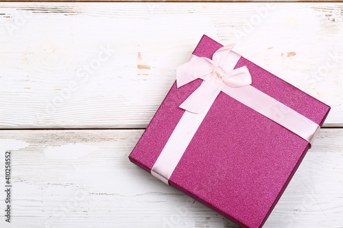 pink gift box with bow on white wooden background