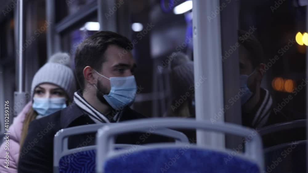 Guy and girl in masks are ride the tram at night Guy and girl in masks are ride the tram at night