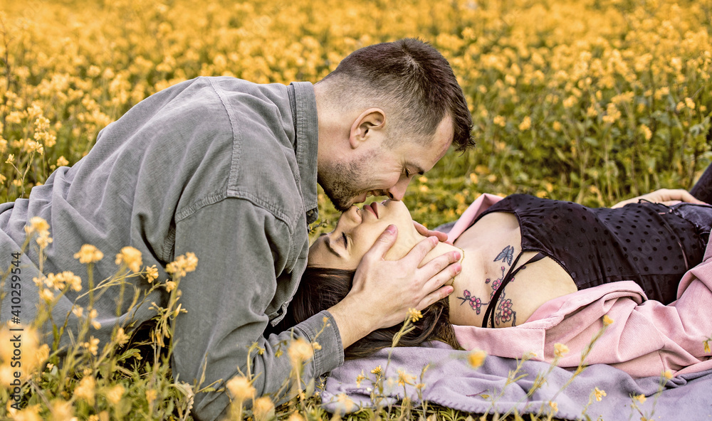 couple lying and kissing in the field with yellow flovers couple lying and kissing in the field with yellow flovers