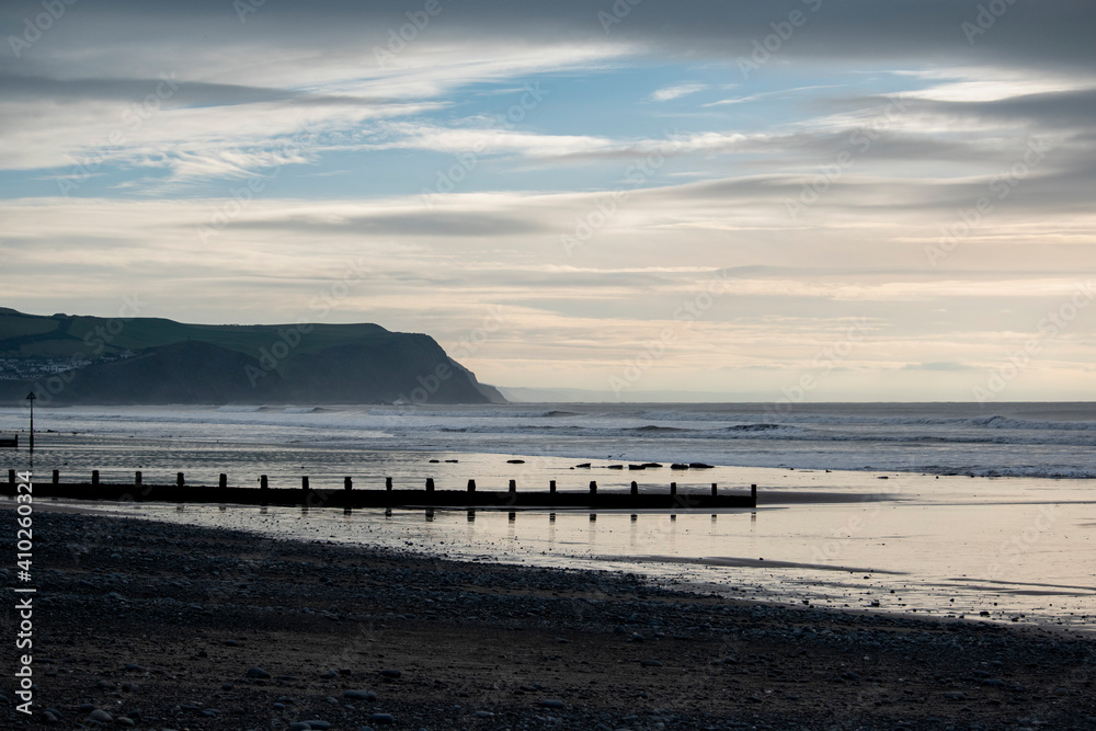 a view of the beach at Borth with a beach groyne across the sand and the cliffs behind it