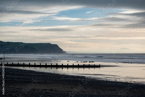 a view of the beach at Borth with a beach groyne across the sand and the cliffs behind it