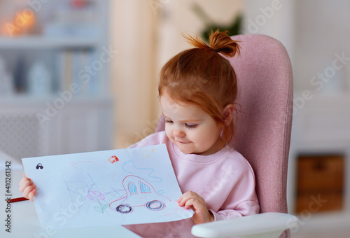 фотографія cute toddler baby girl showing her drawing, that was done with colour pencils