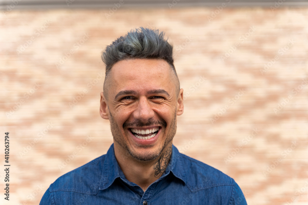 Cheerful handsome man with highlights in hair against wall Cheerful handsome man with highlights in hair against wall