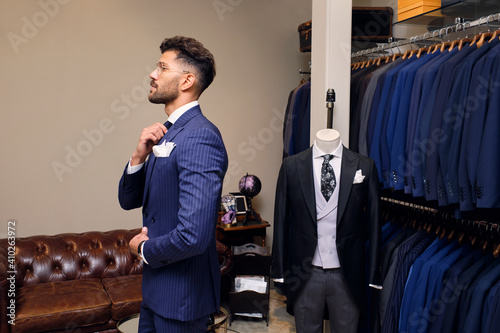 Man trying on blue pinstripe suit in tailors boutique photo