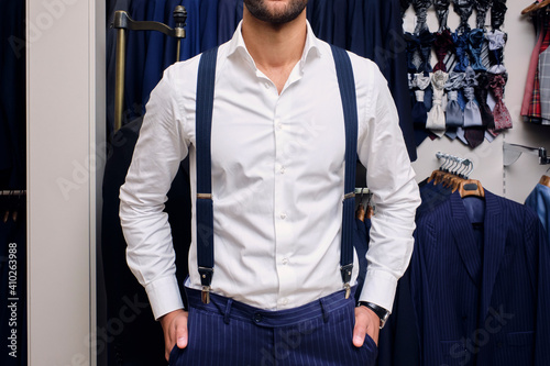 Customer in white shirt and blue suspenders¬†in tailors boutique photo