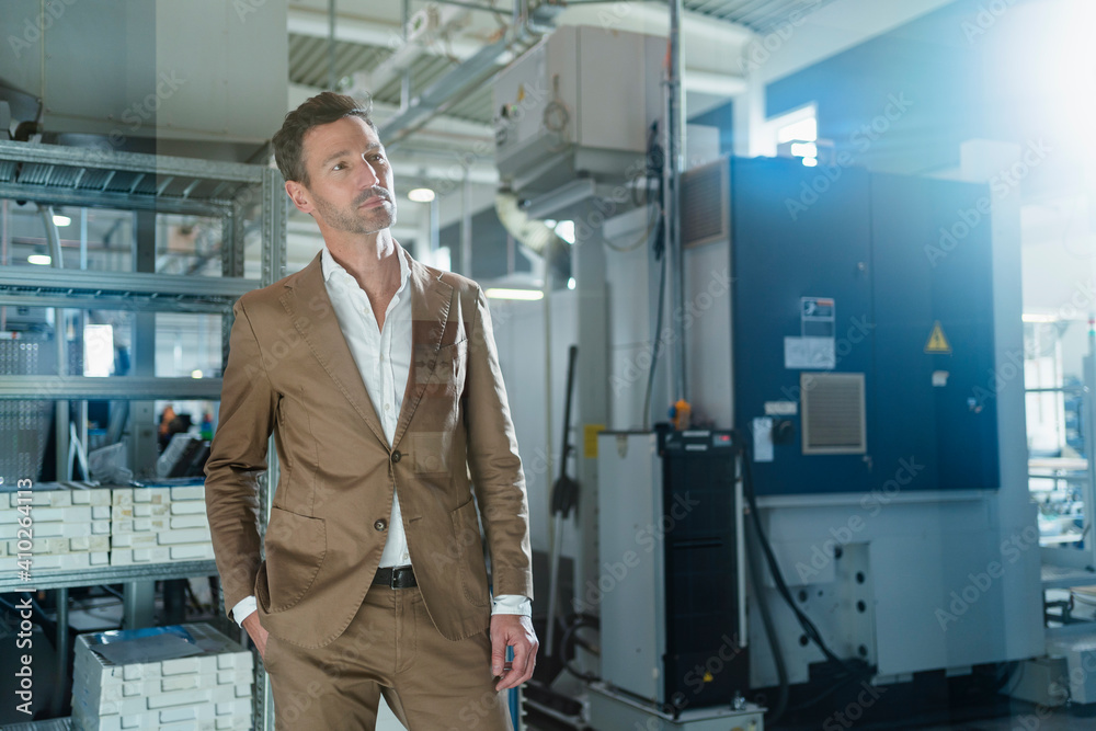 Mature businessman with hands in pockets contemplating at factory Mature businessman with hands in pockets contemplating at factory