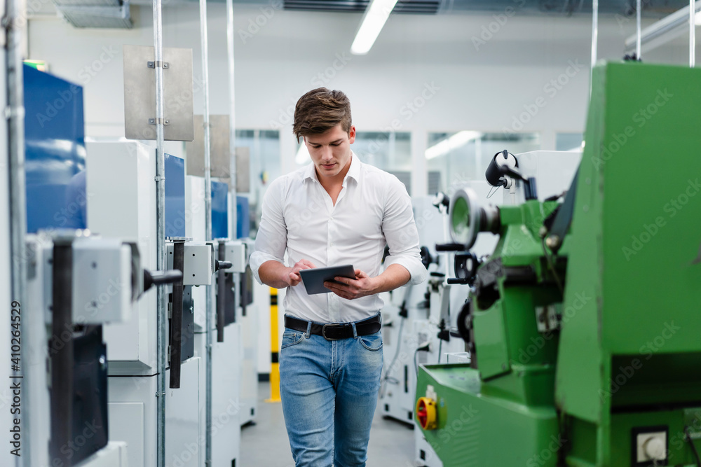 Young businessman walking while using digital tablet in factory Young businessman walking while using digital tablet in factory