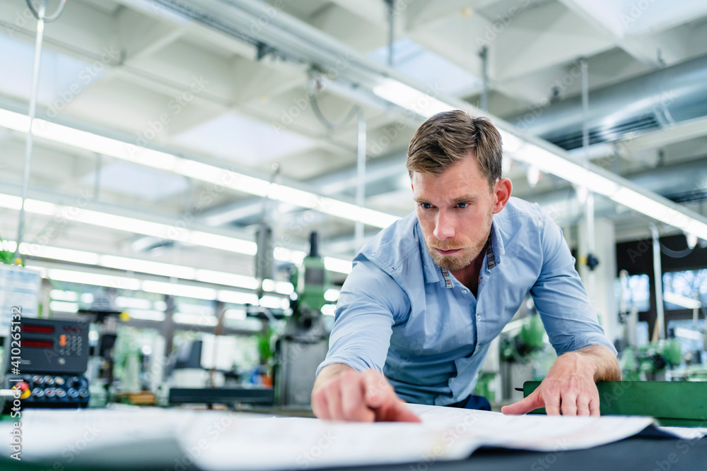 Male engineer looking over floor plan in industry Male engineer looking over floor plan in industry