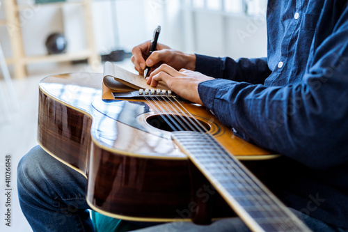 Male composer writing in note pad while sitting at studio