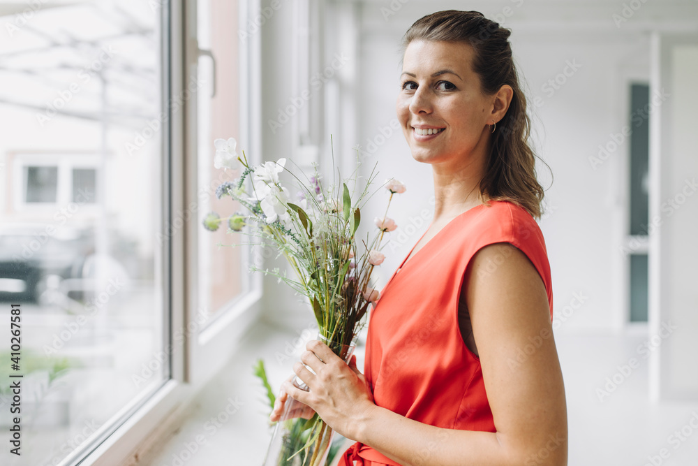 Portrait of smiling woman with flowers at window Portrait of smiling woman with flowers at window