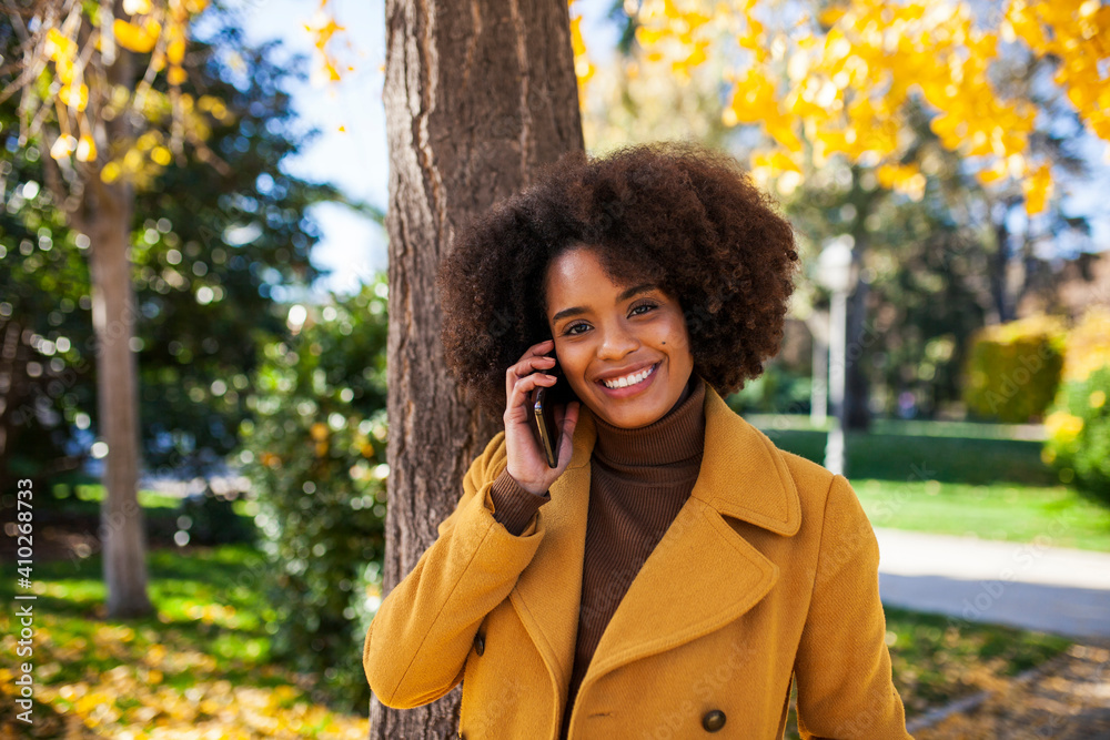 Smiling woman talking on mobile phone while standing at park