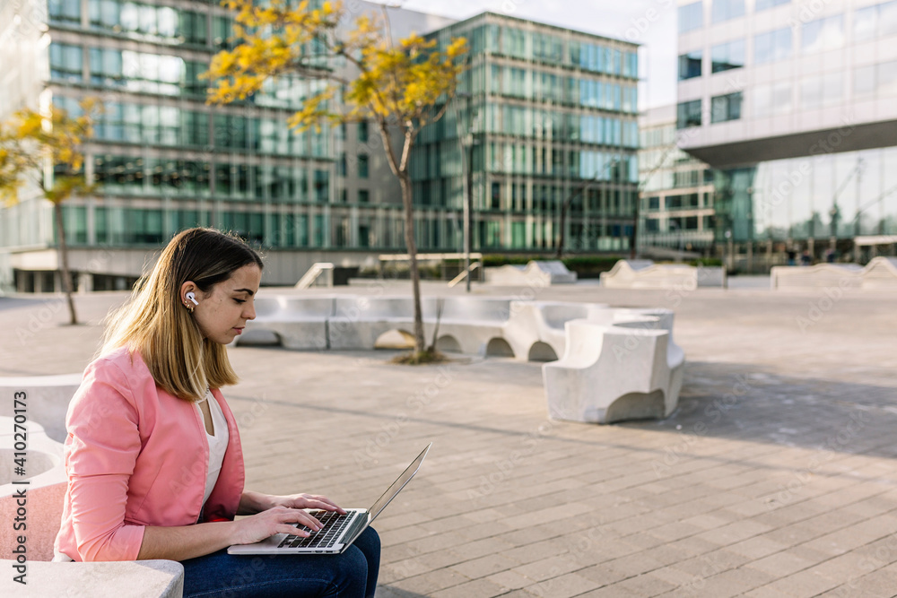 Spain, Barcelona, Young businesswoman using laptop in front of office buildings Spain, Barcelona, Young businesswoman using laptop in front of office buildings