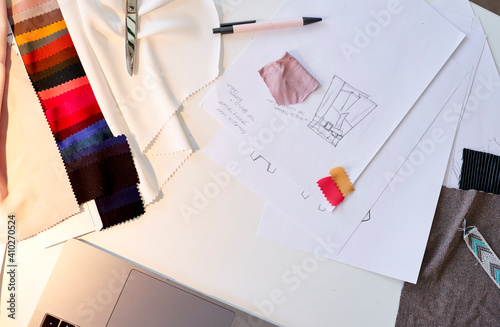 Design on paper with fabric swatches at desk in atelier