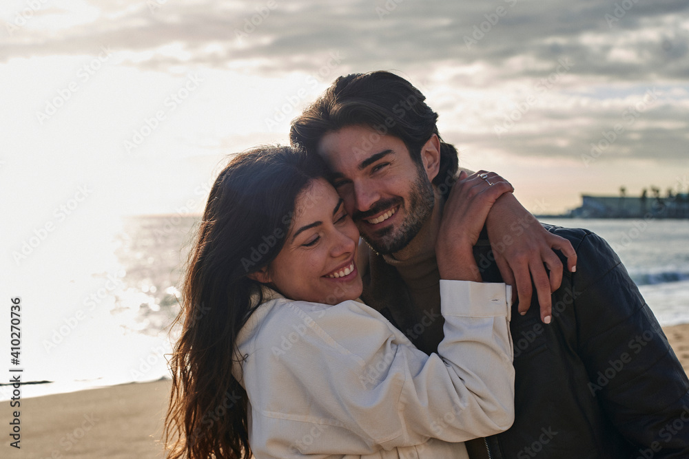 Smiling woman embracing man while standing at beach Smiling woman embracing man while standing at beach