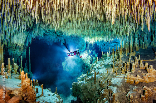 Male cave diver exploring amidst stalactite and stalagmite in sea, Cenote Uku Cusam, Quintana Roo, Mexico photo