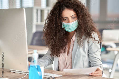 Brazilian woman in protective mask working in front of a computer, Poland, podkarpackie, Dƒôbica photo