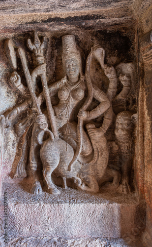 Aihole, Karnataka, India - November 7, 2013: Ravanaphadi Cave Shiva Temple. Brown stone sculpture of goddess Durga defeating buffalo with trident.  photo