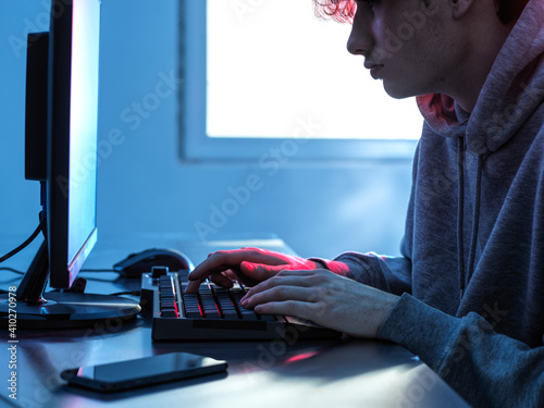 Midsection of teenage boy breaching data from computer on desk photo