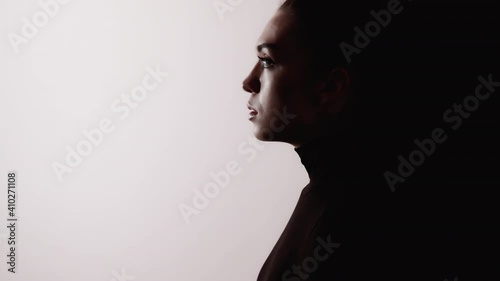 Female silhouette. Domestic violence. Abuse harassment. Dark contrast profile outline of disturbed anxious woman face isolated on white copy space background with black shadow. photo