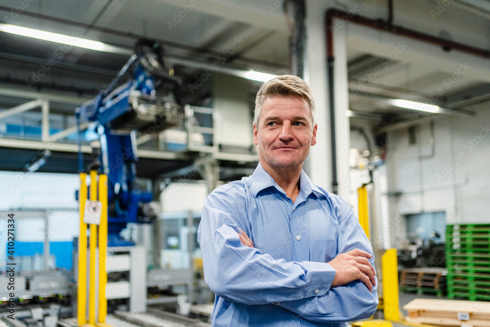 Smiling supervisor with arms crossed looking away in industry Smiling supervisor with arms crossed looking away in industry