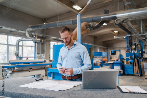 Portrait of carpenter examining documents in production hall