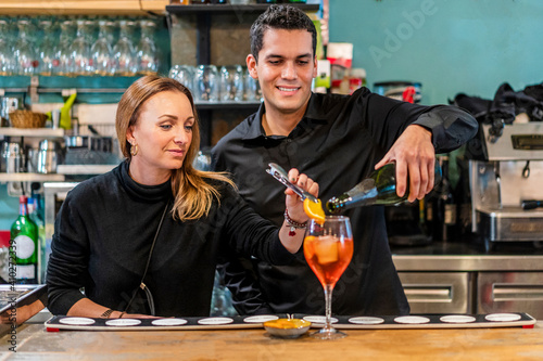 Female bartender preparing cocktail with male assistant photo