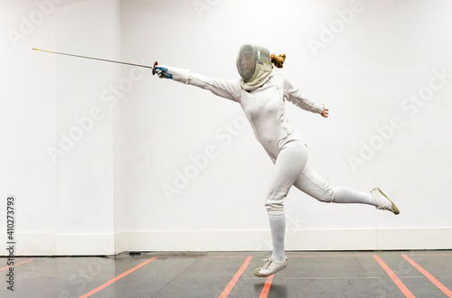 Woman¬†in fencing outfit practicing at gym