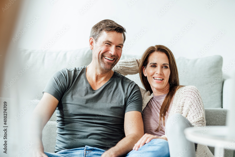 Happy mature couple looking away at home