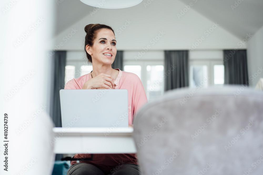 Happy mature businesswoman with laptop day dreaming while sitting in home office Happy mature businesswoman with laptop day dreaming while sitting in home office