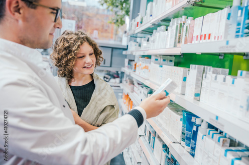 Pharmacist recommending medicine to smiling customer in chemist shop