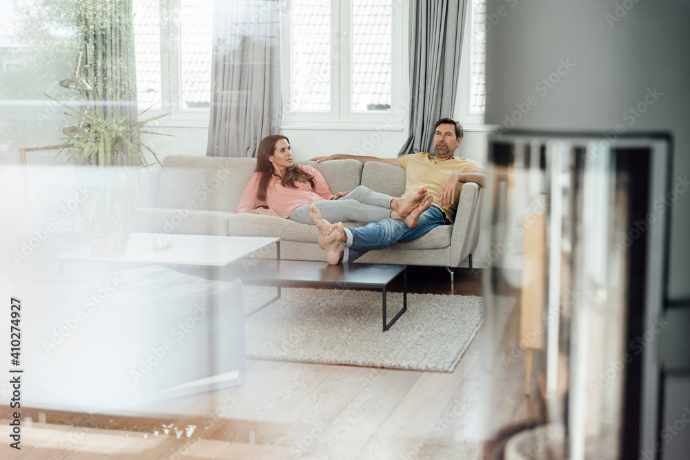 Mature couple relaxing together on sofa while talking in living room Mature couple relaxing together on sofa while talking in living room